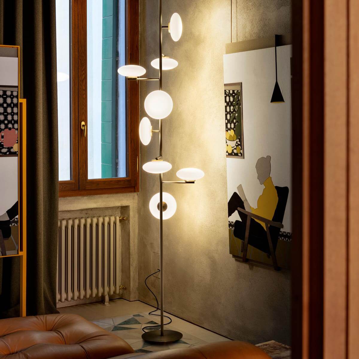 Arya Floor-to-Ceiling Lamp featuring illuminated opal glass discs arranged along a slender architectural frame in black and gold finishes, designed for luxury contemporary interiors