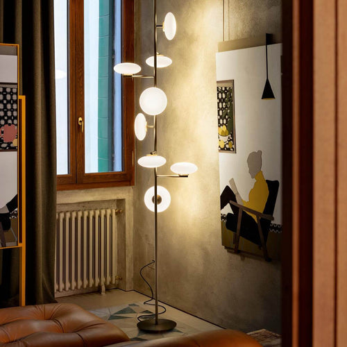 Arya Floor-to-Ceiling Lamp featuring illuminated opal glass discs arranged along a slender architectural frame in black and gold finishes, designed for luxury contemporary interiors