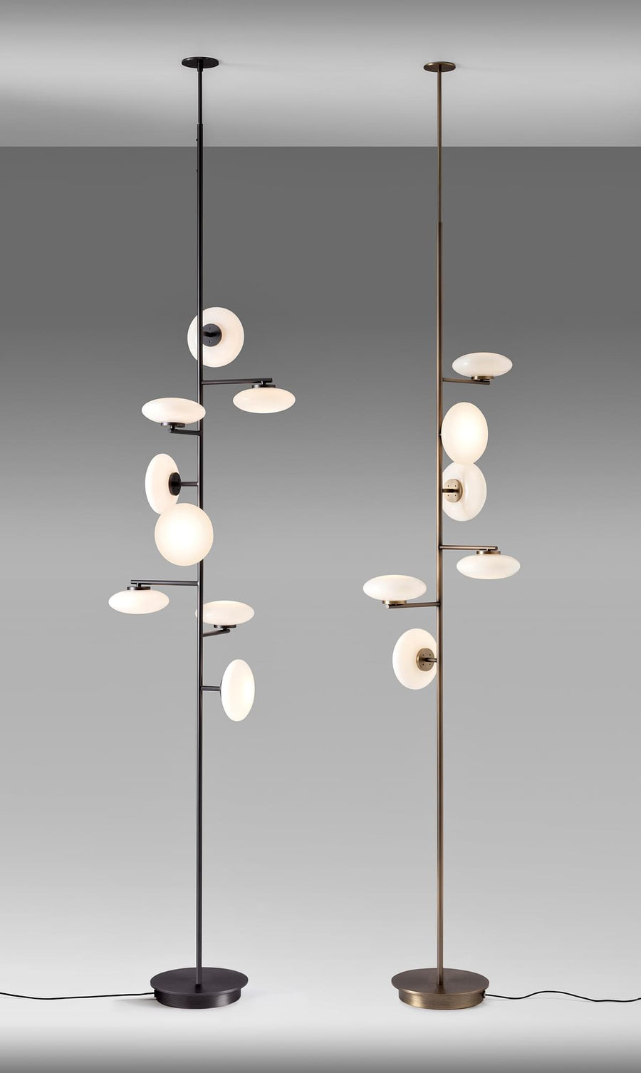 Arya Floor-to-Ceiling Lamp featuring illuminated opal glass discs arranged along a slender architectural frame in black and gold finishes, designed for luxury contemporary interiors