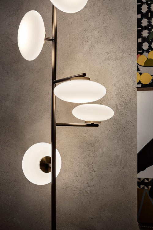Arya Floor-to-Ceiling Lamp featuring illuminated opal glass discs arranged along a slender architectural frame in black and gold finishes, designed for luxury contemporary interiors