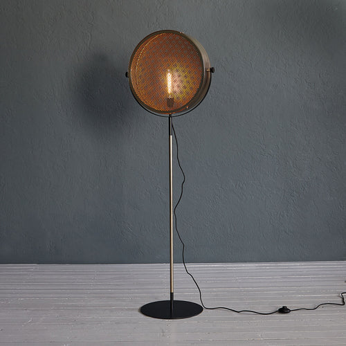 Gold industrial floor lamp with perforated spotlight shade and modern metal stand in a contemporary interior.