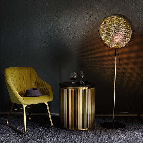 Gold industrial floor lamp with perforated spotlight shade and modern metal stand in a contemporary interior.