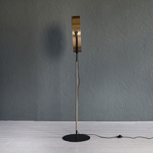 Gold industrial floor lamp with perforated spotlight shade and modern metal stand in a contemporary interior.