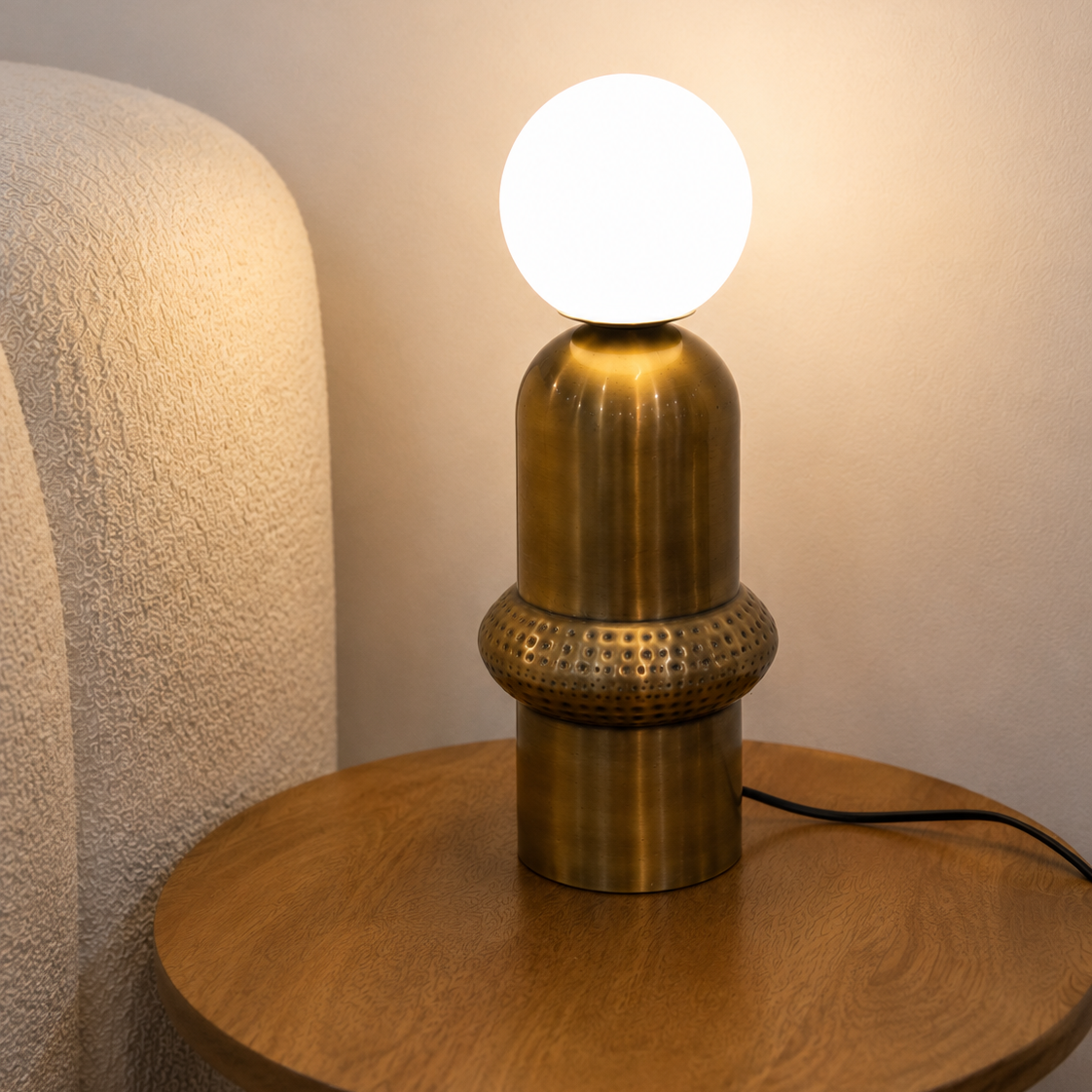 Aureon Table Lamp featuring a brushed brass sculptural base with handcrafted textured detailing and a frosted glass globe, designed for modern luxury interiors.