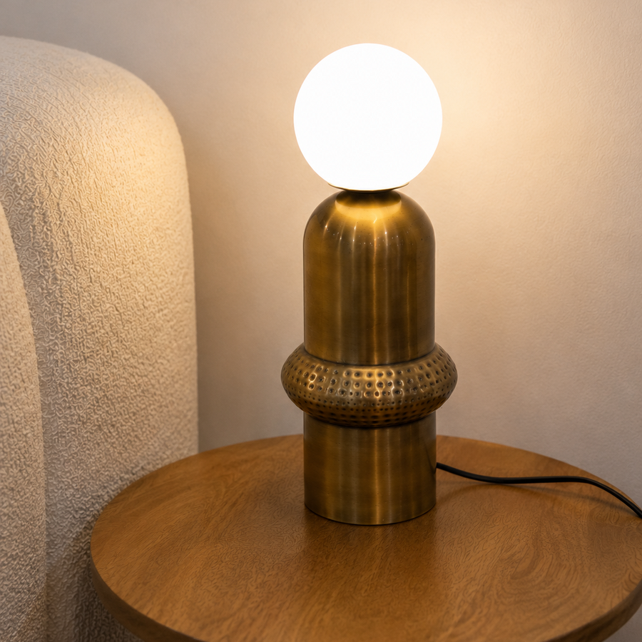 Aureon Table Lamp featuring a brushed brass sculptural base with handcrafted textured detailing and a frosted glass globe, designed for modern luxury interiors.