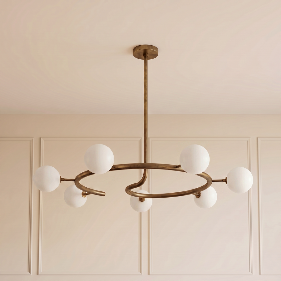 Helix Halo Chandelier with a sculptural brushed brass circular frame and seven matte milk glass globes, creating elegant ambient lighting for contemporary luxury interiors