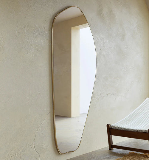 Irregular gold full length mirror mounted on wall in modern interior