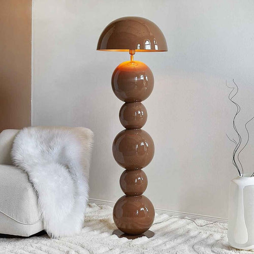 Sculptural brown metal floor lamp with stacked spherical base and dome shade in a modern minimalist interior.