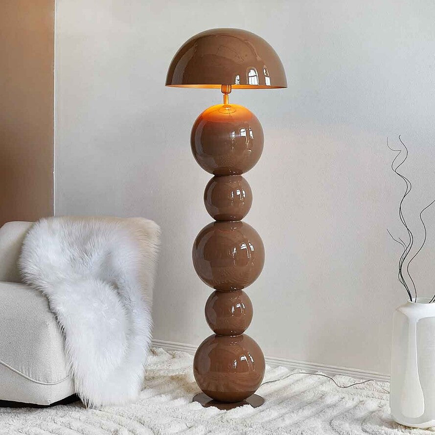 Sculptural brown metal floor lamp with stacked spherical base and dome shade in a modern minimalist interior.