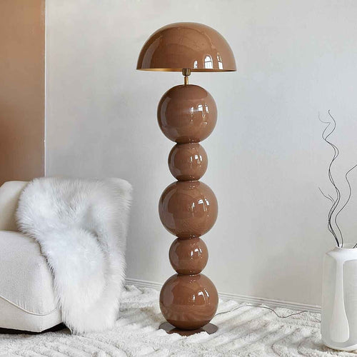 Sculptural brown metal floor lamp with stacked spherical base and dome shade in a modern minimalist interior.