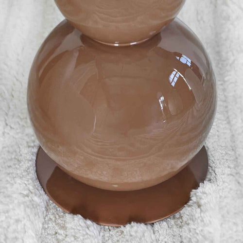 Sculptural brown metal floor lamp with stacked spherical base and dome shade in a modern minimalist interior.